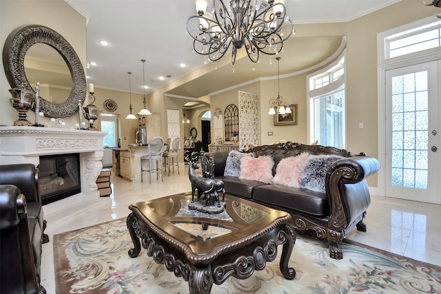 living room featuring a chandelier, ornamental molding, a healthy amount of sunlight, and a glass covered fireplace