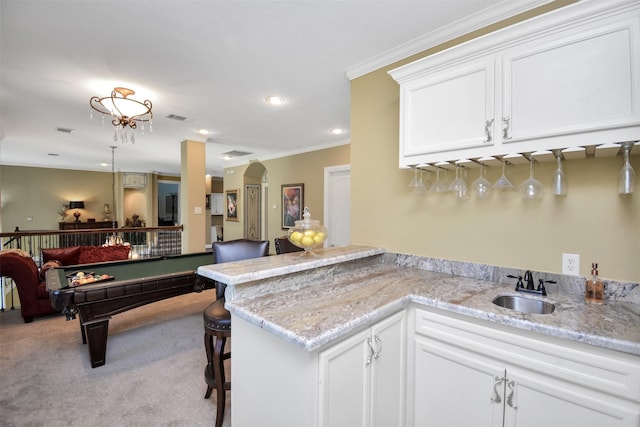 kitchen featuring visible vents, a sink, white cabinets, open floor plan, and carpet