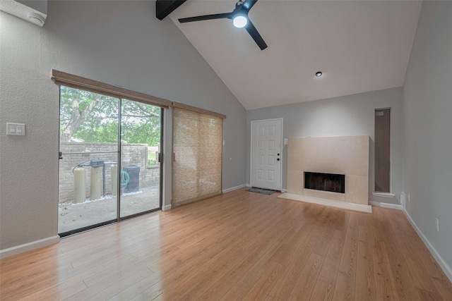 unfurnished living room with a ceiling fan, light wood finished floors, beam ceiling, and high vaulted ceiling