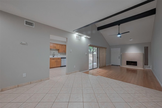 unfurnished living room with a ceiling fan, visible vents, a fireplace, a sink, and lofted ceiling with beams