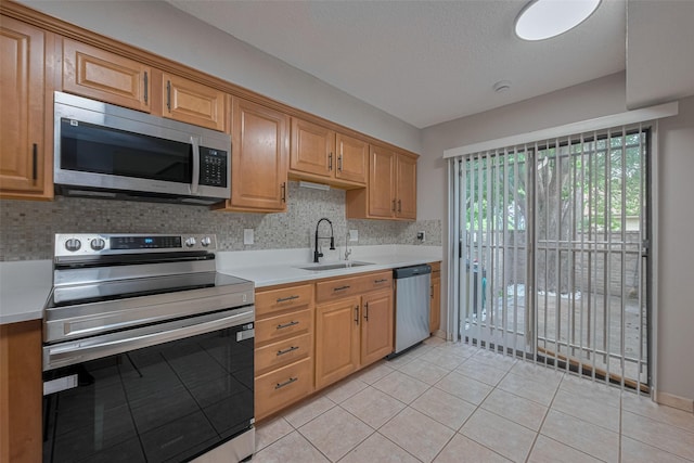 kitchen featuring light countertops, a sink, light tile patterned floors, and stainless steel appliances