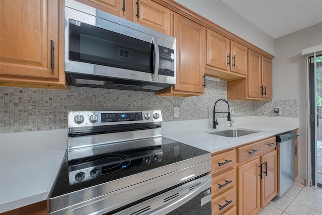 kitchen with light countertops, stainless steel appliances, decorative backsplash, and a sink