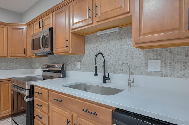 kitchen with decorative backsplash, light countertops, a sink, light tile patterned floors, and stainless steel appliances
