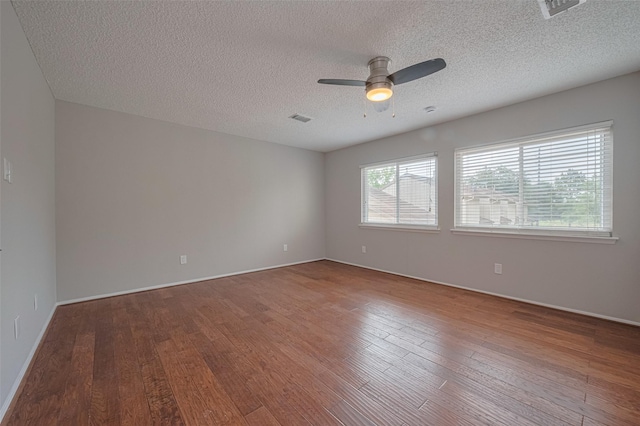 empty room with visible vents, a ceiling fan, wood-type flooring, and a textured ceiling