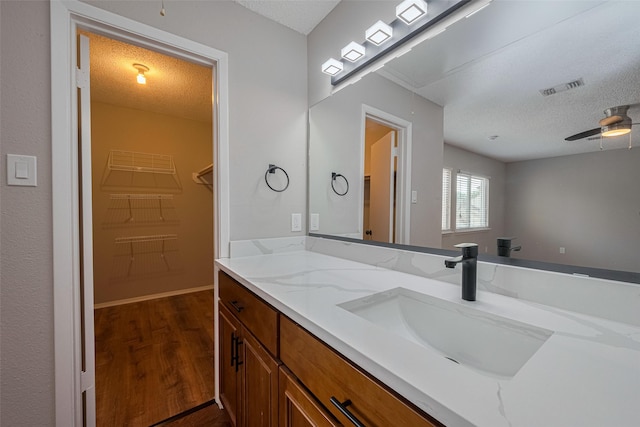 bathroom featuring a textured ceiling, visible vents, wood finished floors, and a spacious closet