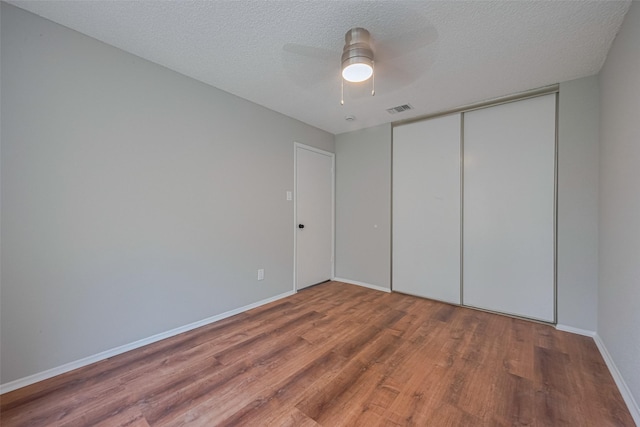 unfurnished bedroom featuring baseboards, visible vents, wood finished floors, and a closet