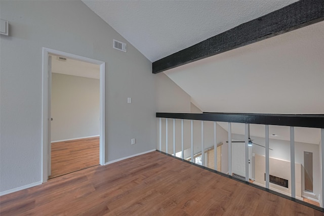 hallway with baseboards, visible vents, vaulted ceiling with beams, and wood finished floors