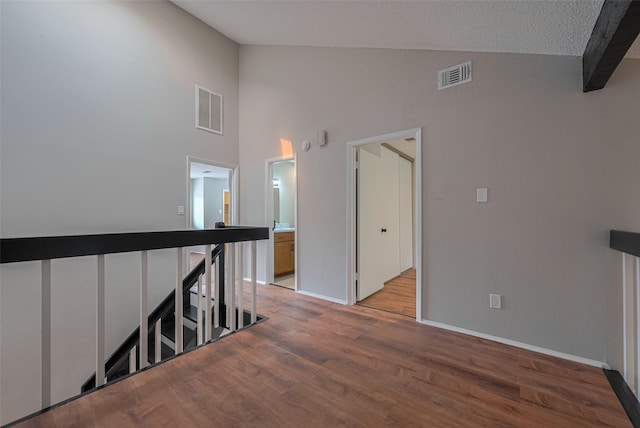 corridor with baseboards, visible vents, an upstairs landing, and light wood-type flooring