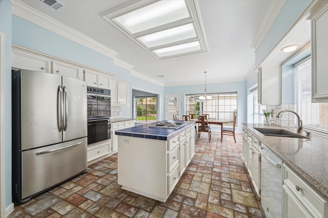 4107 Pebble Beach Dr, League City, TX 77573 - kitchen with stainless steel appliances, a sink, tile countertops, white cabinetry, and brick flooring