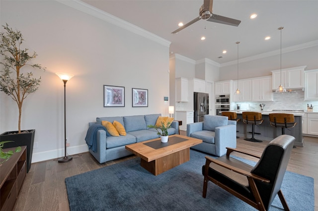living room with ceiling fan, a towering ceiling, crown molding, wood finished floors, and recessed lighting