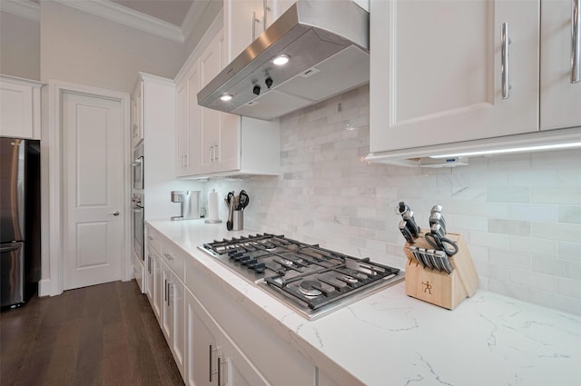 kitchen with crown molding, white cabinetry, appliances with stainless steel finishes, backsplash, and exhaust hood