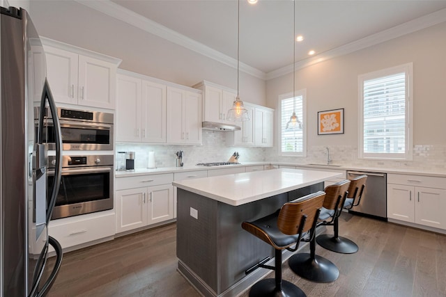 kitchen with crown molding, a breakfast bar, stainless steel appliances, and white cabinetry