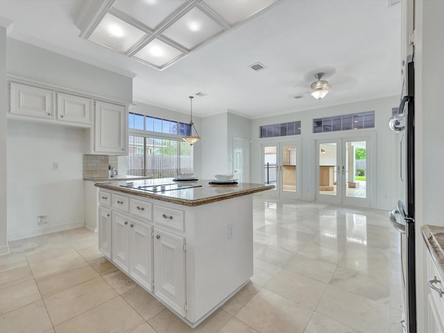 kitchen featuring electric cooktop, a center island, a ceiling fan, and white cabinetry