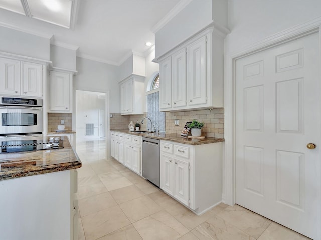 kitchen with crown molding, tasteful backsplash, a sink, stainless steel appliances, and white cabinetry