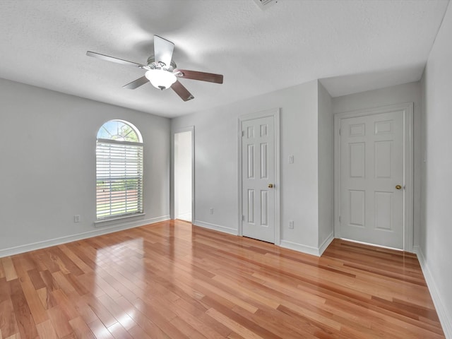 unfurnished bedroom featuring a textured ceiling, ceiling fan, baseboards, and light wood-style floors