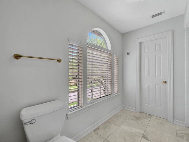 interior space featuring toilet, baseboards, visible vents, and marble finish floor