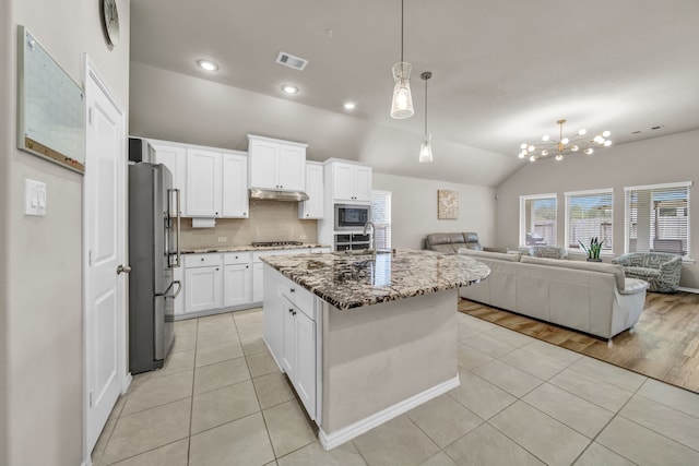11430 Raven Claw Dr, Tomball, TX 77375 - kitchen featuring appliances with stainless steel finishes, open floor plan, light tile patterned flooring, stone counters, and lofted ceiling