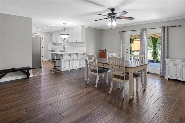 dining space with baseboards, ornamental molding, ceiling fan, and dark wood-type flooring