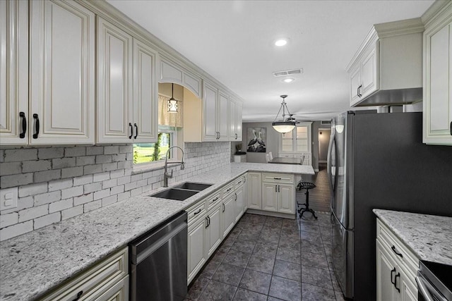 kitchen featuring visible vents, a peninsula, a sink, appliances with stainless steel finishes, and backsplash