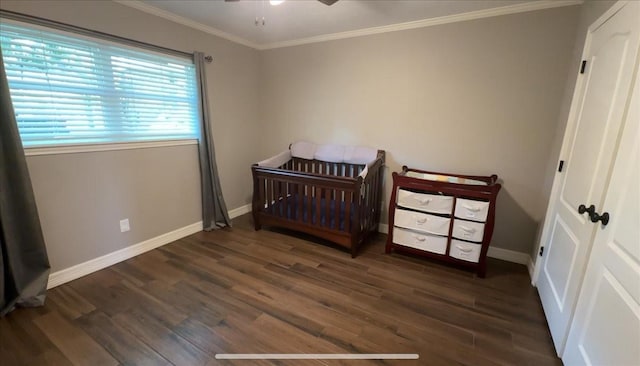 bedroom featuring crown molding, wood finished floors, baseboards, ceiling fan, and a crib