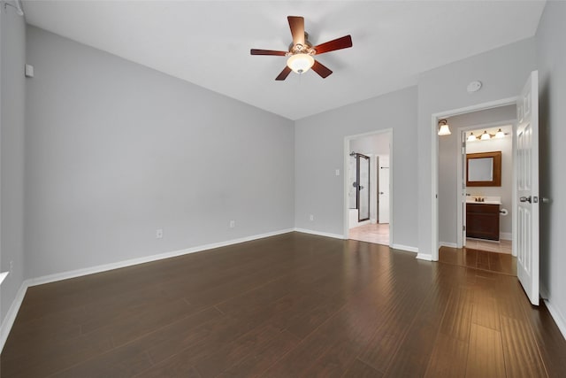 unfurnished bedroom featuring baseboards, dark wood finished floors, and ensuite bath