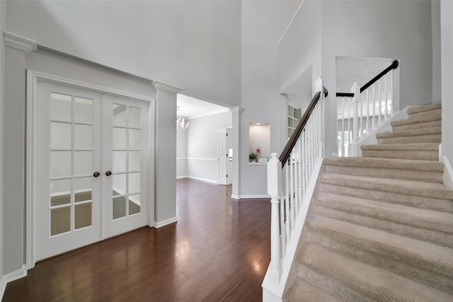 stairs with a high ceiling, french doors, baseboards, wood finished floors, and ornate columns