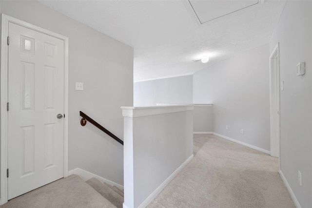 corridor featuring light colored carpet, baseboards, and an upstairs landing