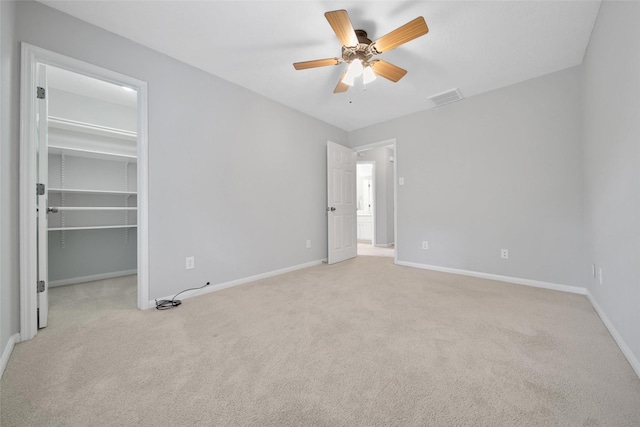 unfurnished bedroom with a spacious closet, baseboards, light carpet, and visible vents