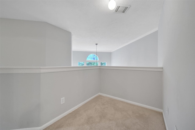 spare room with carpet floors, baseboards, vaulted ceiling, and visible vents