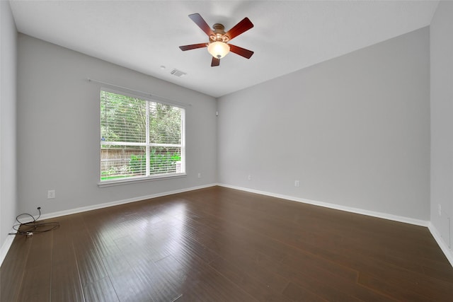 unfurnished room with baseboards, a ceiling fan, dark wood finished floors, and visible vents