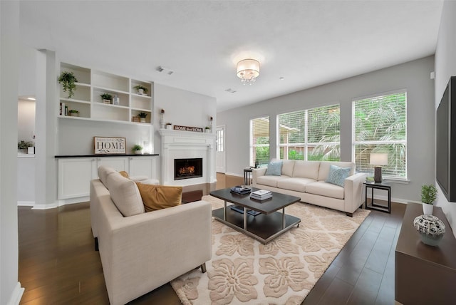 living area featuring baseboards, visible vents, a fireplace, and dark wood-type flooring