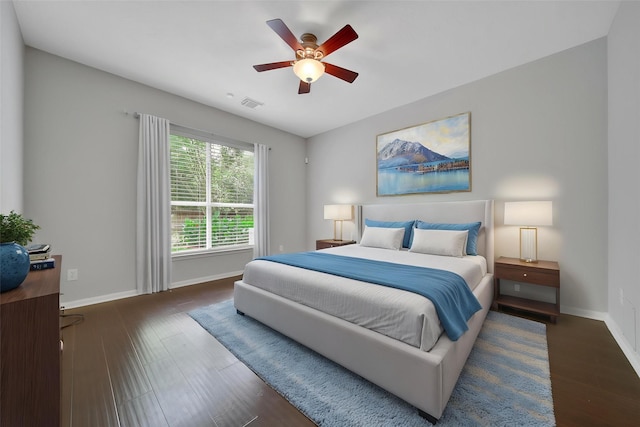 bedroom featuring baseboards, a ceiling fan, wood finished floors, and visible vents