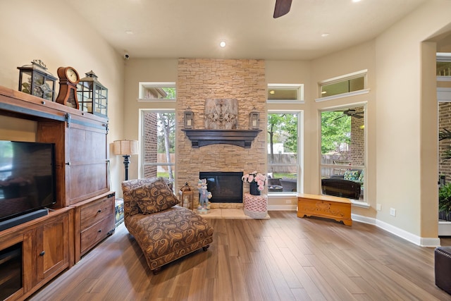 13105 Parc Cove Ct, Cypress, TX 77429 - living room with a ceiling fan, a stone fireplace, wood finished floors, healthy amount of natural light, and a high ceiling