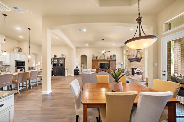 13105 Parc Cove Ct, Cypress, TX 77429 - dining space featuring a fireplace, arched walkways, light wood finished floors, ceiling fan, and recessed lighting