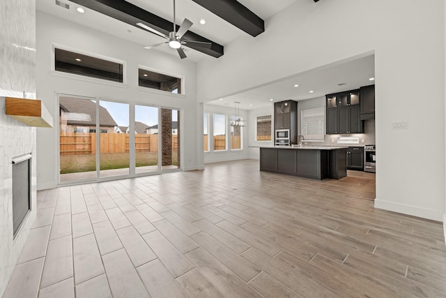 unfurnished living room with baseboards, ceiling fan, beamed ceiling, and recessed lighting