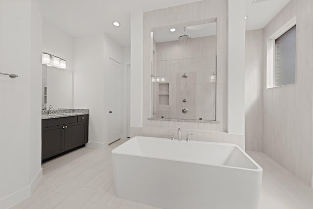 bathroom featuring vanity, a freestanding tub, a tile shower, and recessed lighting