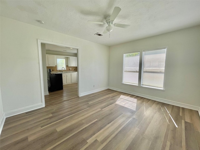 spare room with a ceiling fan, baseboards, visible vents, and wood finished floors