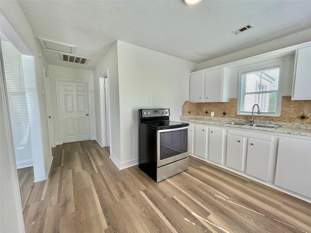 kitchen featuring visible vents, a sink, electric stove, and light wood-type flooring