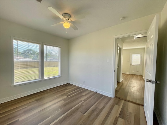 empty room with baseboards, ceiling fan, and wood finished floors