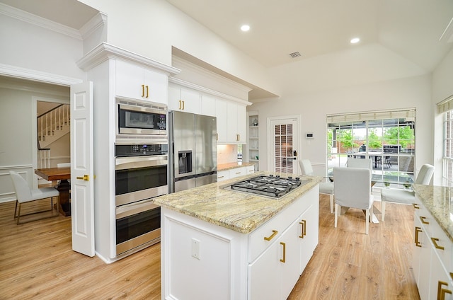 kitchen featuring crown molding, light stone countertops, light wood-type flooring, a center island, and stainless steel appliances