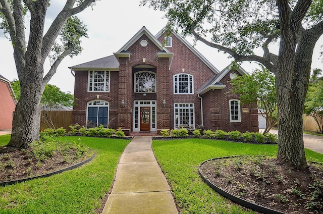 view of front of property with brick siding, a front lawn, and fence