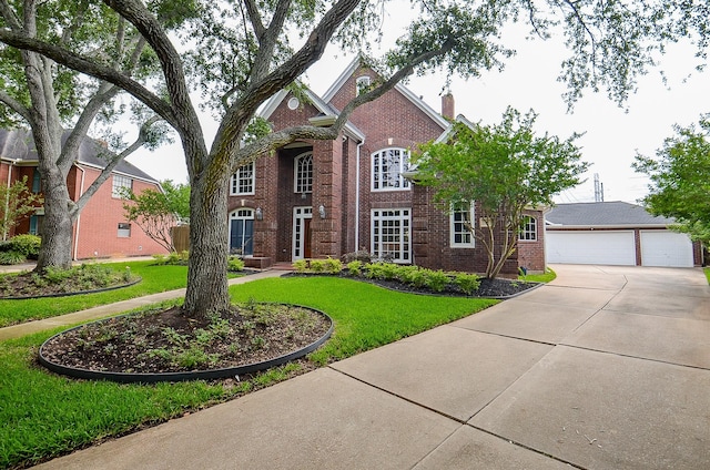 traditional-style house featuring brick siding, a garage, a chimney, and a front lawn