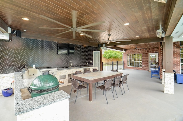 view of patio / terrace featuring a ceiling fan, outdoor dining area, exterior kitchen, a sink, and fence