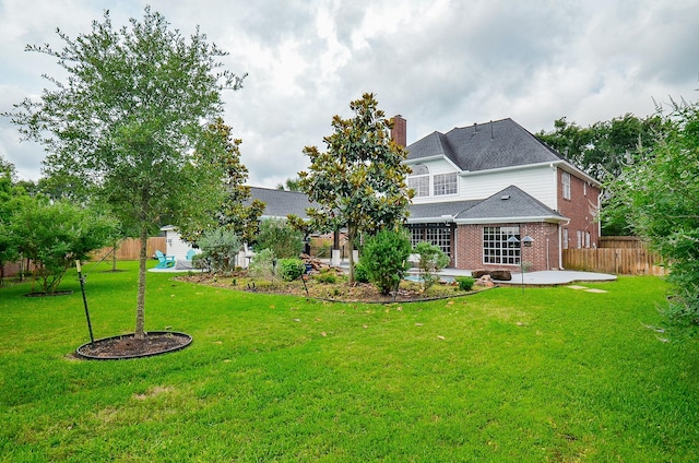 back of house with fence, brick siding, a chimney, a patio, and a yard