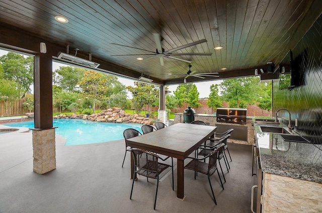 view of patio featuring grilling area, a sink, a fenced in pool, a fenced backyard, and an outdoor kitchen