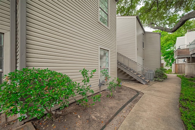view of home's exterior with stairway, fence, and central air condition unit