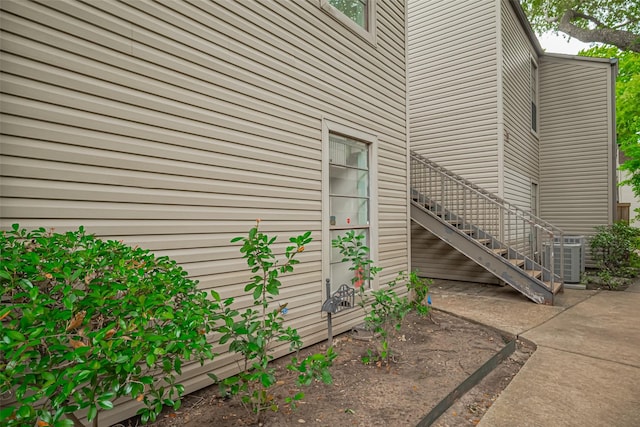 view of property exterior with central AC unit, stairs, and a patio area