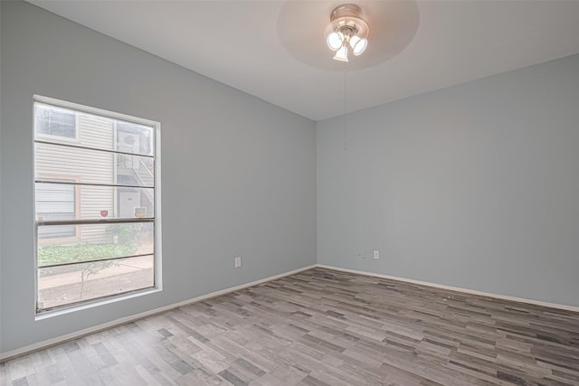spare room featuring plenty of natural light, a ceiling fan, baseboards, and wood finished floors