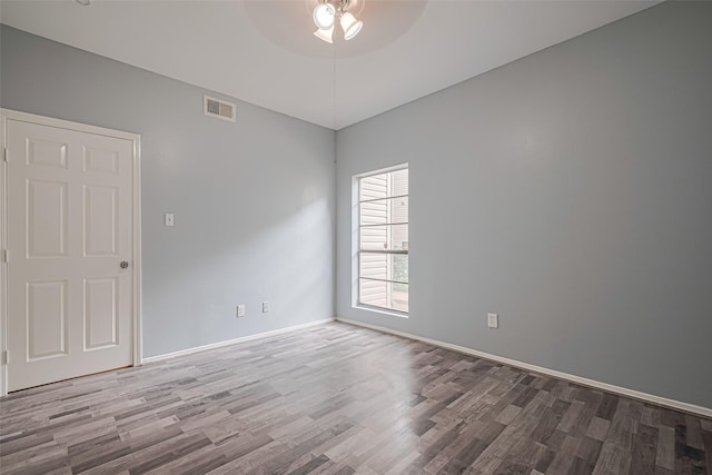 spare room with baseboards, ceiling fan, visible vents, and wood finished floors