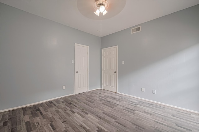 spare room with baseboards, ceiling fan, wood finished floors, and visible vents